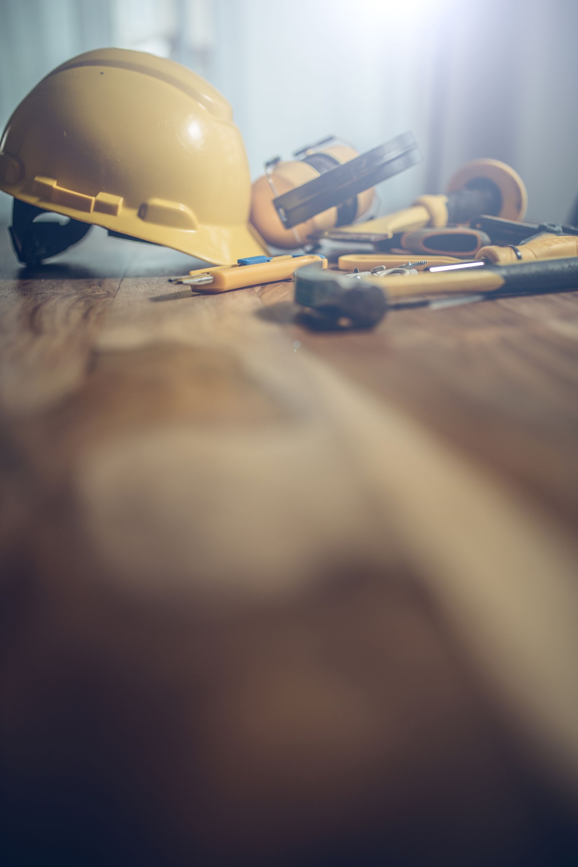 Construction tools and a yellow helmet on a wood table
